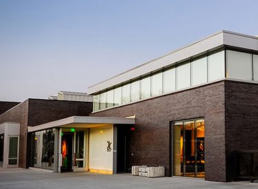 Outside of a large, modern grey hotel building